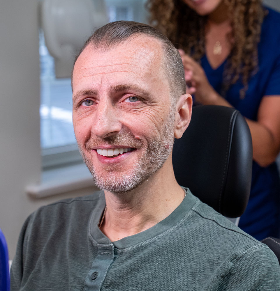 patient smiling brightly after their full mouth implant procedure